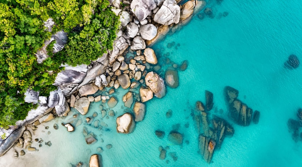 Granite boulders in crystal-clear turquoise water from above