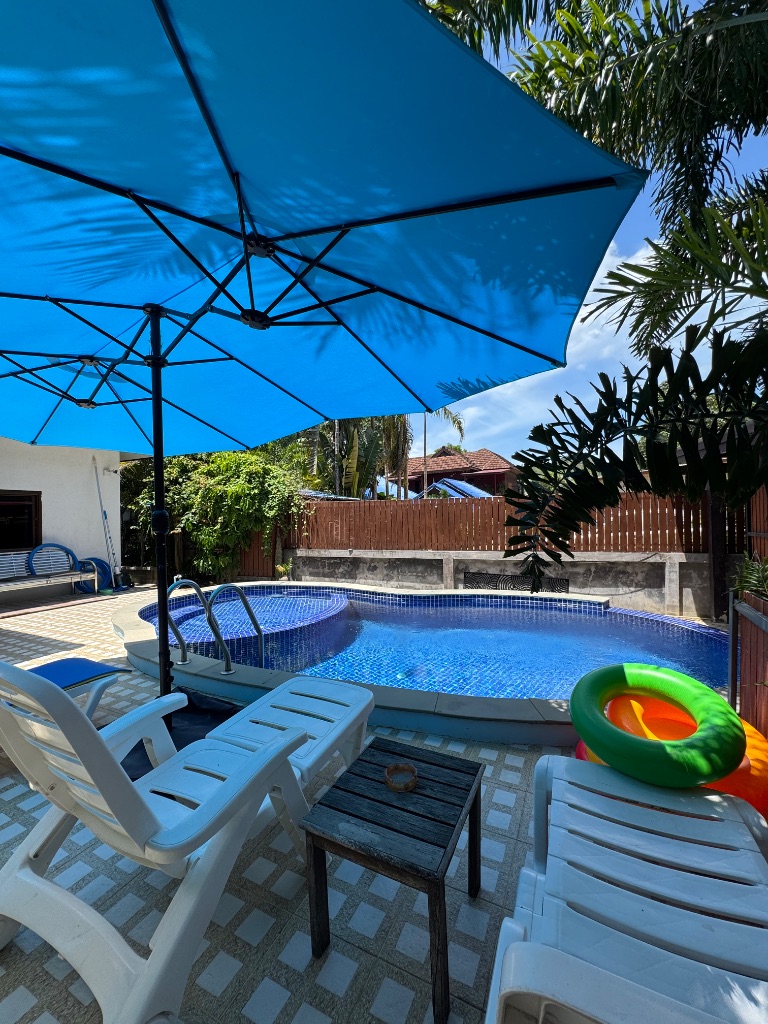 Pool with sun loungers and blue umbrella at Su's House