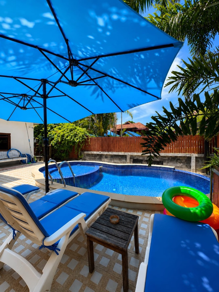 The Villa — pool with sun loungers and blue umbrellas